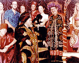 A still taken during the shooting of a sequence from The Magic Show at the Variety Arts Theatre in Los Angeles, 1982. From left to right: Allen Bracken (seated), Dave Egan (third from left), Don Bice, Orson Welles (seated), Bruce Gold, Oja Kodar and Kiki, Abb Dickson, and a female magic assistant.